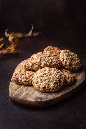 Homemade oatmeal cookies on a wooden cutting board. Dark background. Rustic styleの写真素材
