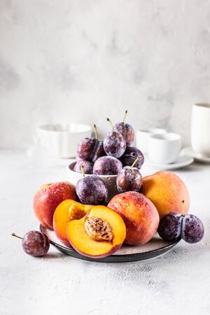 Still life of plums and peaches on a white backgroundの写真素材