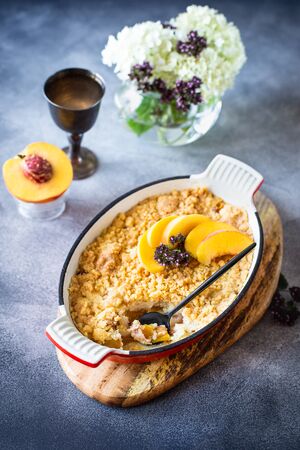 Homemade peach scramble with sand crumbs in a metal baking dishの写真素材