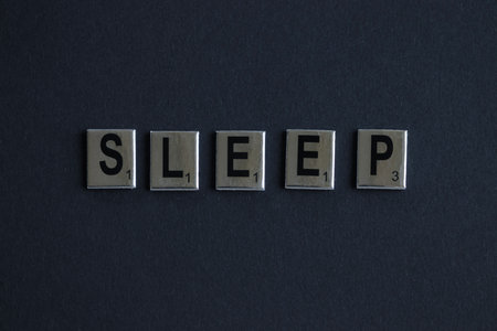 The word SLEEP made of board game letters on a dark background. High quality photoの写真素材