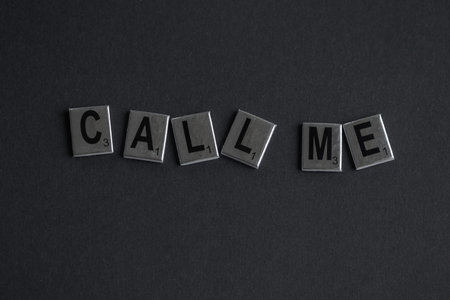 The words CALL ME made of board game letters on a dark background. High quality photo