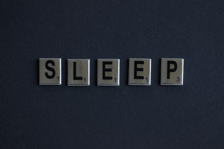 The word SLEEP made of board game letters on a dark background