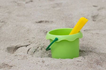 Green bucket and yellow shovel lying on sand at the beach. High quality photoの写真素材