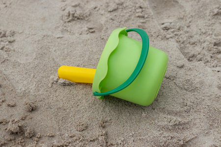 Green bucket and yellow shovel lying on sand at the beach. High quality photoの写真素材