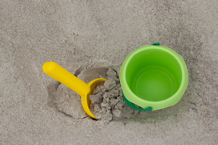 Green bucket and yellow shovel lying on sand at the beach. High quality photoの写真素材