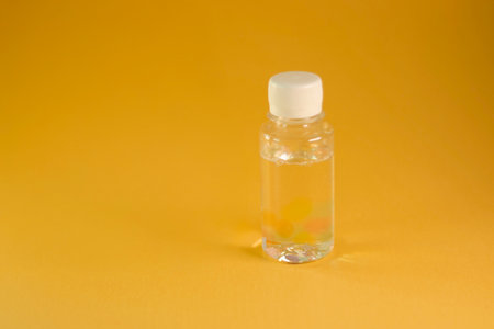 Clear plastic bottle with liquid on yellow background. High quality photoの写真素材