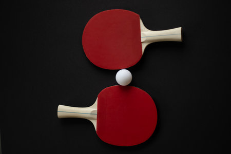 Two red table tennis paddles and a white ball arranged on a black background. High quality photoの写真素材