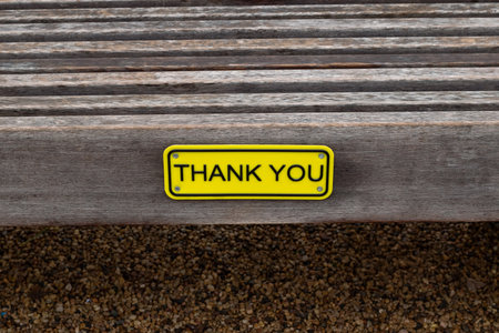 Yellow THANK YOU sign attached to a wooden bench.の写真素材