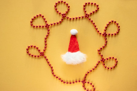 Christmas hat and red bead garland decoration on yellow backgroundの写真素材