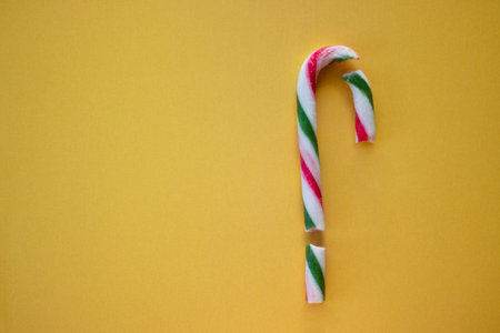 Broken Christmas candy cane on yellow background