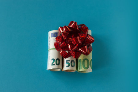 Money gift euro bills with decorative bow on a blue background. High quality photo