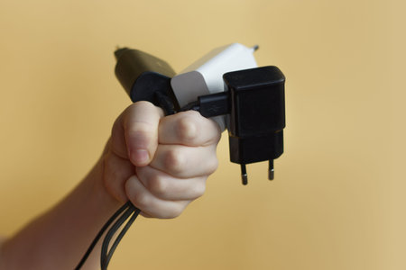 Electronic chargers in a child hand on yellow background
