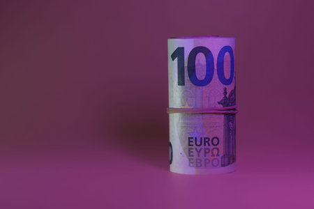 Rolled 100 euro banknotes on purple background. High quality photo