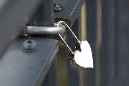Heart shaped love padlock on metal fence close up