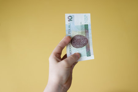 Hand holding Polish 10 zloty banknote on yellow backgroundの写真素材