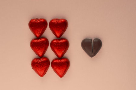 Red chocolate hearts and broken dark heart on light background