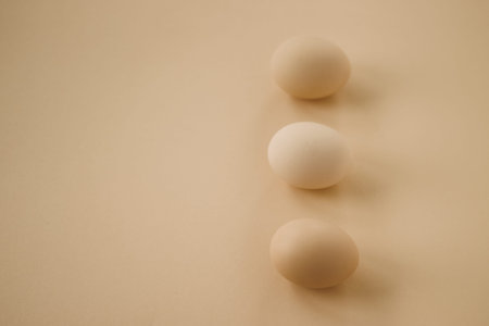 Three brown eggs on minimalist beige background