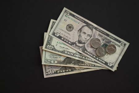 US dollar banknotes and coins on black background