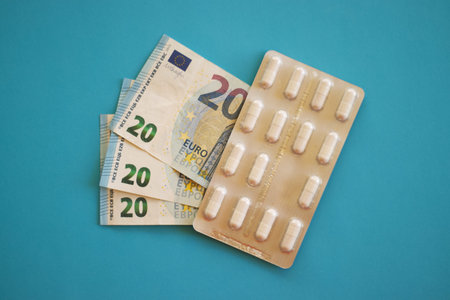 Blister pack of capsules next to 20 euro banknotes on a blue background