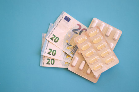 Blister packs of capsules placed next to 20 euro banknotes on a blue background