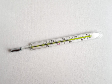 Close Up Traditional medical mercury-in-glass thermometer for measuring high 38Â°C body temperature in hand. High temperature or fever is a symptom of many diseases including virus infection.の写真素材