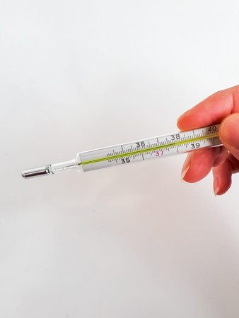 Womans hand holding medical thermometer measuring a temperature. High temperature. Fever is a...