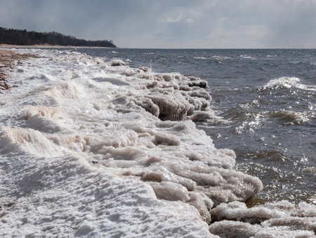 Seascape depicting landscape of Baltic sea and beach with ice and snow formations on the shore in bright sunlight. Frozen ice blocks and sea water in winterの写真素材