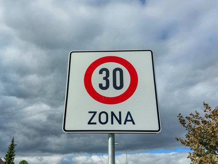 Metal road or traffic sign with number 30 in a red circle, and zone, indicating new speed limit...