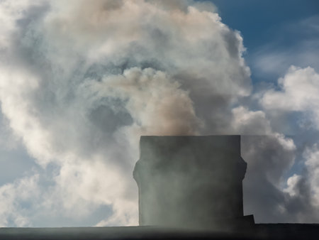 View of a house chimney with white and grey dense smoke from burning firewood, pellets or briquettes for heating indoorsの写真素材