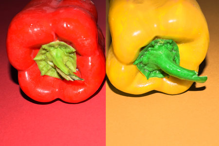 one red sweet bell pepper and one yellow bell pepper isolated on red and yellow background, produce,...
