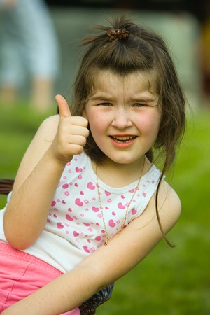 Beautiful young girl as a happy child showing palm thumb. の写真素材