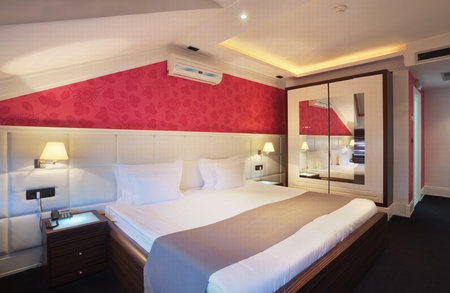 Interior of a hotel room for two, double bed and red wallpapers. の写真素材