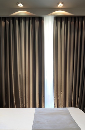 Part of a hotel room, just a bed and curtain with two lights. の写真素材