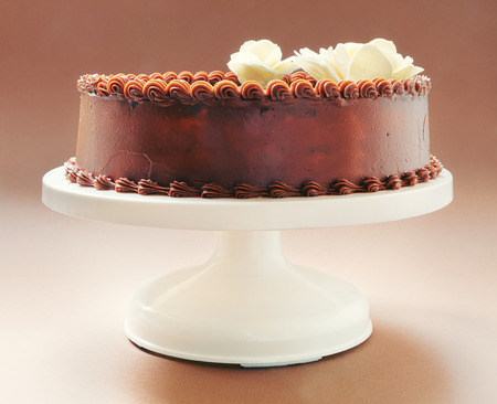 All chocolate birthday cake, on brown background, decorated with yellow flowers on top  の写真素材