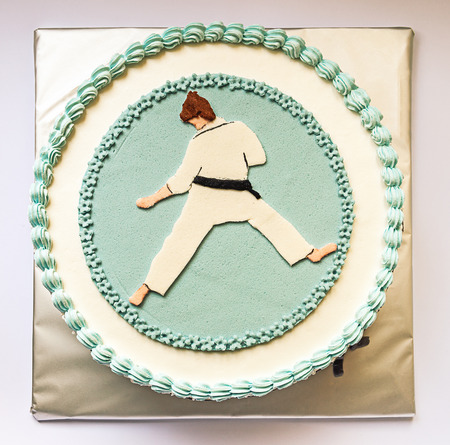 Birthday cake decorated with karate silhouette, in blue and white on gray background   の写真素材