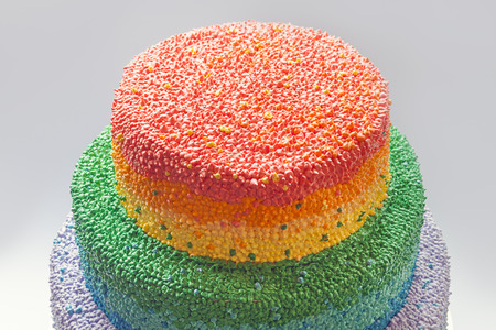 Details of a birthday cake decorated with cream in rainbow colors.の写真素材