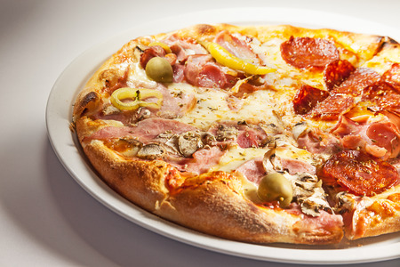 Pizza with ham on one side and sausages on the other.の写真素材