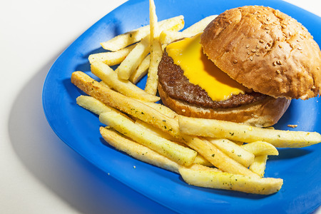 Blue plate with simple hamburger with slice of cheese and french fries.の写真素材