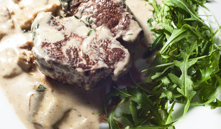 Steak in cream and mushrooms, served on white plate.の写真素材
