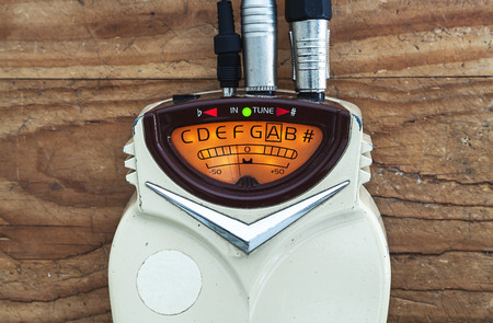Details of an old guitar tuner, solid built with dust on surface, turned on.の写真素材
