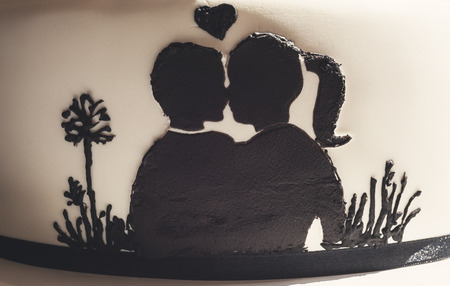 Details of a wedding cake, white sugar cream and black silhouettes.の写真素材