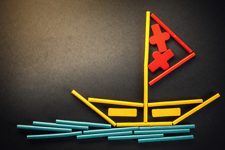 Funny composition presents lonely boat on sea, made of wooden sticks in various colors.の写真素材