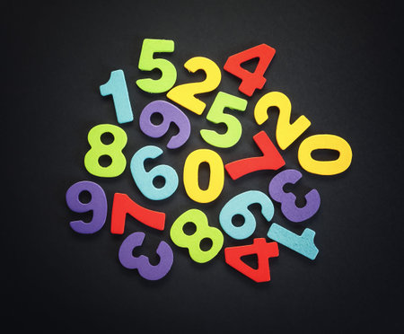 Wooden numbers on black background, various colors, accentuated center of an image.の写真素材