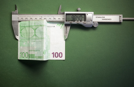 Conceptual composition representing money devaluation symbolically showed with sliding calliper measuring a hundred euros.の写真素材