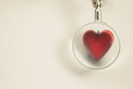 Symbolically showed examination of a heart souvenir in shape of heart viewed through magnifier.の写真素材