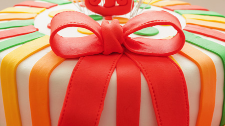 Closeup view on red sugar ribbon decoration of colorful birthday cake.の写真素材