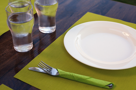 Lunch time, prepared table for lunch, empty white plates and glasses of water.の写真素材