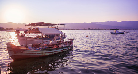 Purple sunset in Greece, two old fishing boats parked, Stavros town in background.の写真素材