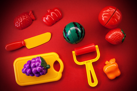 Plastic fruits and vegetables as toys, on red background.の写真素材