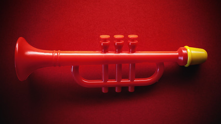 Small red trumpet as a toy, on red background.の写真素材